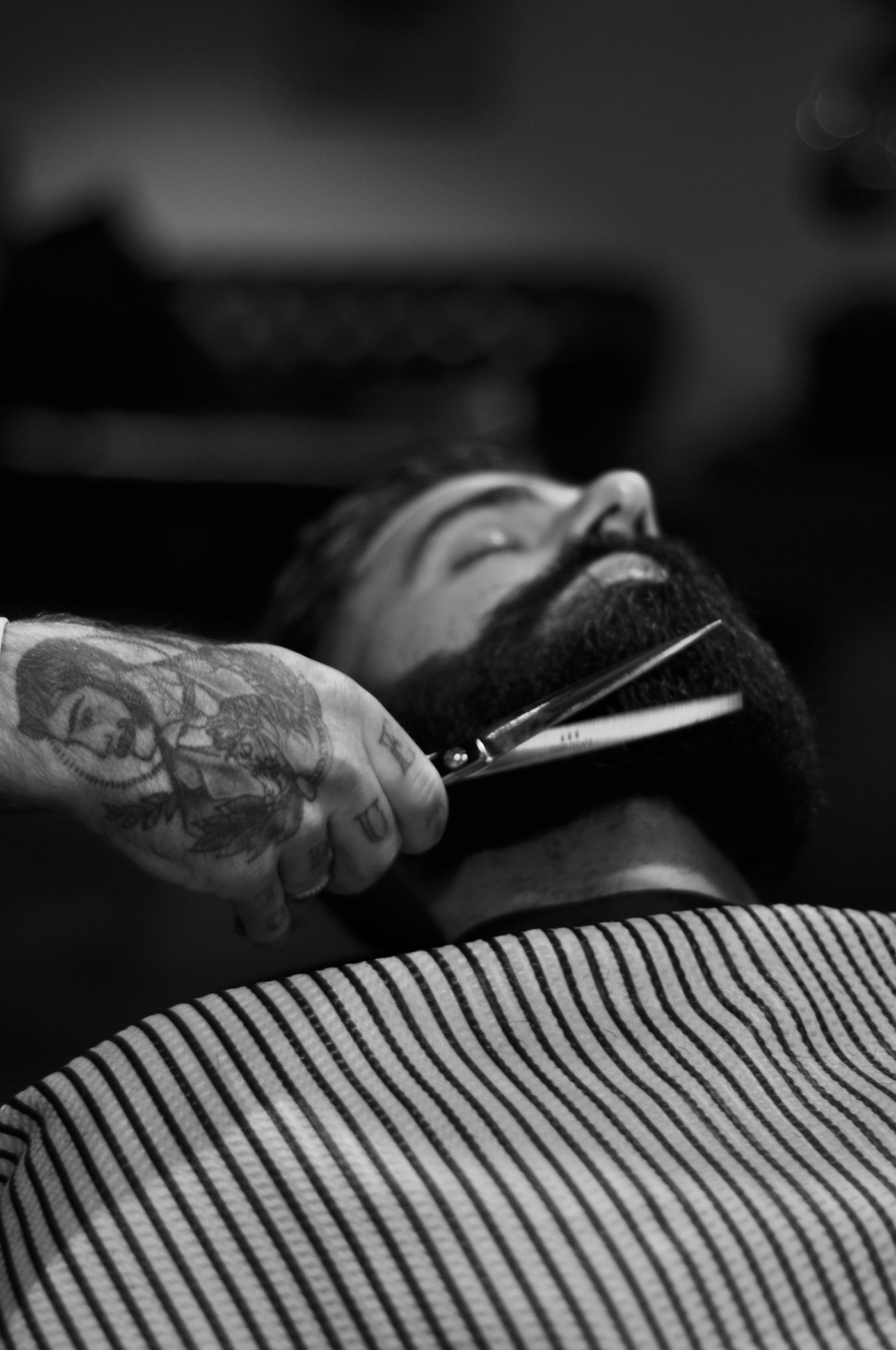 Barber trimming a beard with scissors, black and white