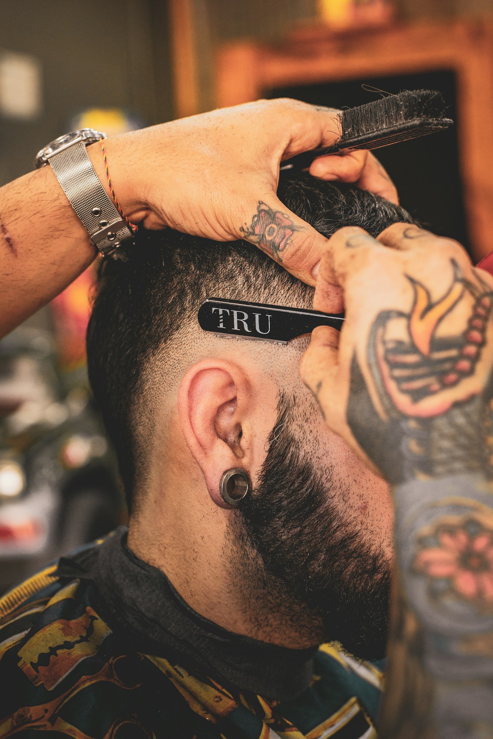 Barber detailing a client's fade with a razor, close on the hands