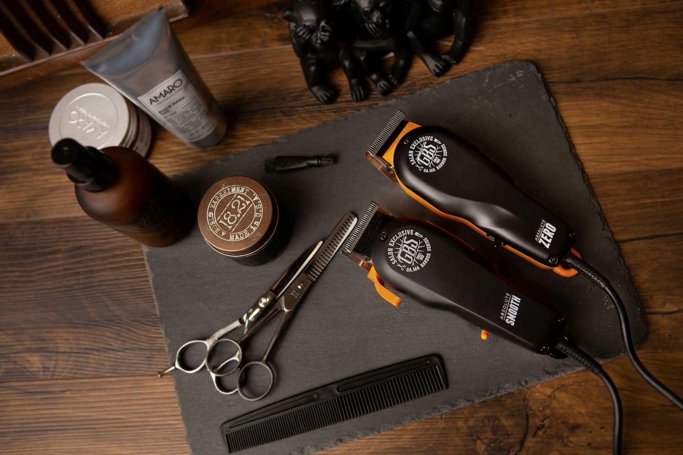 Clippers, scissors, comb and grooming products laid out on slate